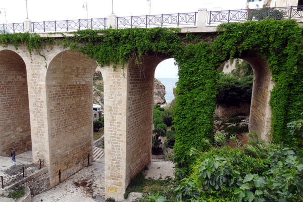 Bro over slugten, som fører til badestranden i Polignano a Mare