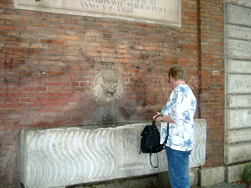 Filling the water bottle by a Roman fountain