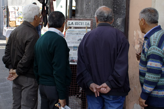M&aelig;nd l&aelig;ser avis p&aring; Gaden i Catania